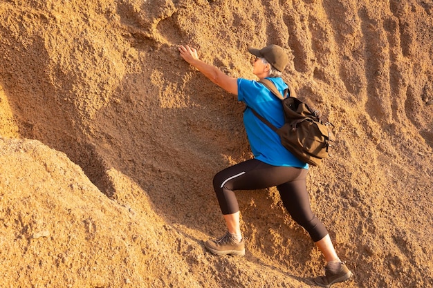 Фото Задний вид женщины, поднимающейся на скалу