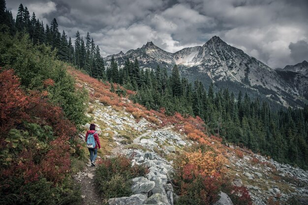 写真 雲の空を背景に山をハイキングしている女性の後ろの景色