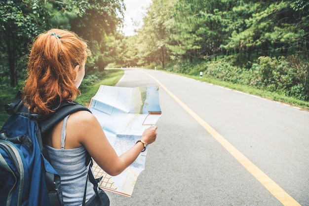 写真 道路で地図を握っている女性の後ろの景色
