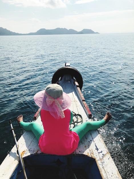 写真 空に向かって海でボートに乗った女性の後ろの景色
