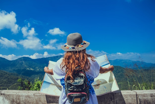 写真 山の向こうに立っている帽子をかぶった女性の後ろの景色