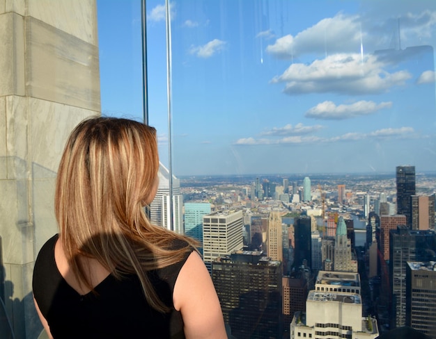 Фото Задний вид женщины, смотрящей на городской пейзаж на фоне неба