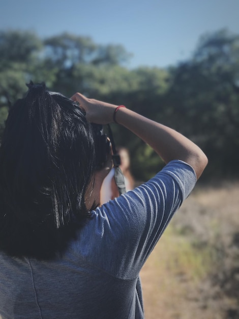 写真 フィールドに立って写真を撮っている女性の後ろの景色