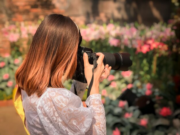 写真 外でカメラで写真を撮っている女性の後ろの景色