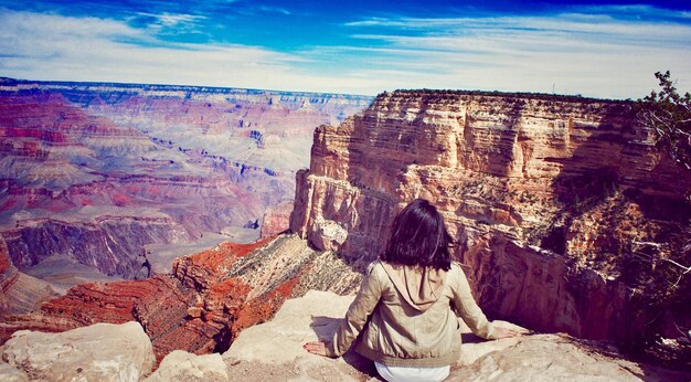 写真 カニオンに座っている女性の後ろの景色