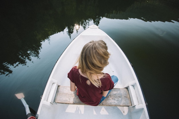 写真 湖で船で航海している女性の後ろの景色