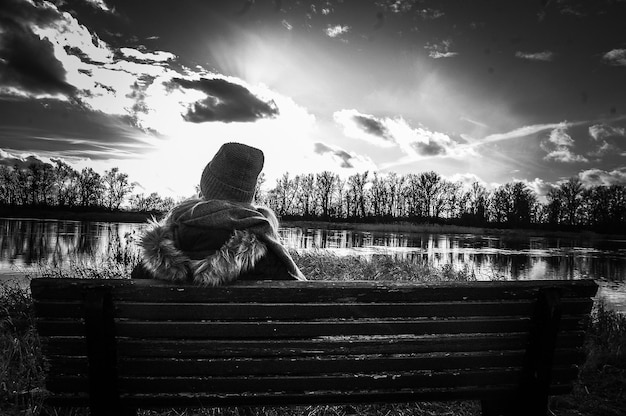 写真 空に向かって湖の上に座っている女性の後ろの景色