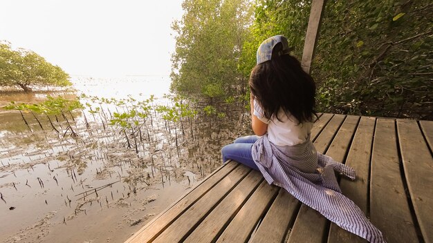 写真 川の上の埠頭に座っている女性の後ろの景色