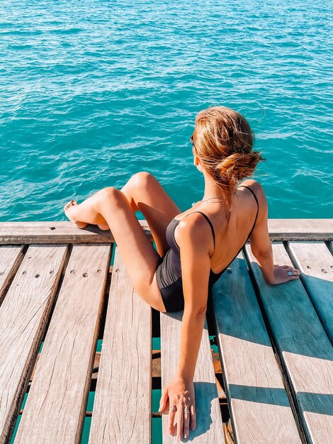 写真 空の向こうの海の上の埠頭に座っている女性の後ろの景色