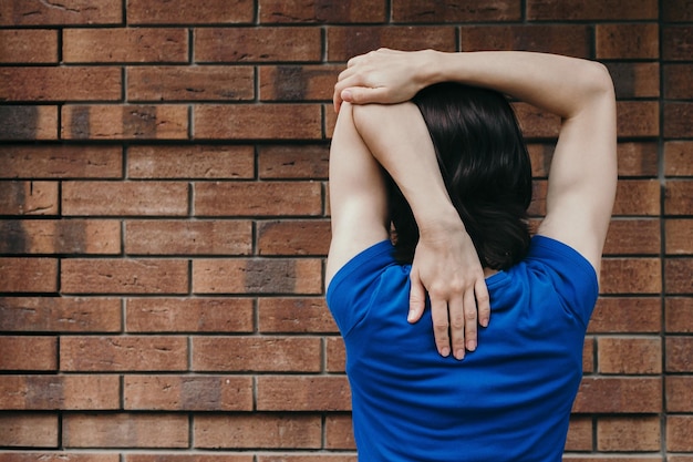 写真 レンガの壁に立っている女性の後ろの景色