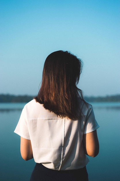 写真 海に向かって立っている女性の後ろの景色