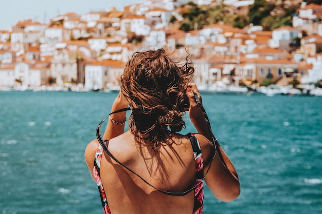 写真 海に向かって立っている女性の後ろの景色