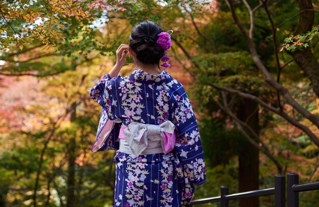 写真 樹木に寄りかかって立っている女性の後ろの景色