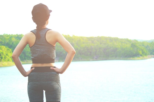 写真 明るい空に照らされて湖のそばに立っている女性の後ろの景色