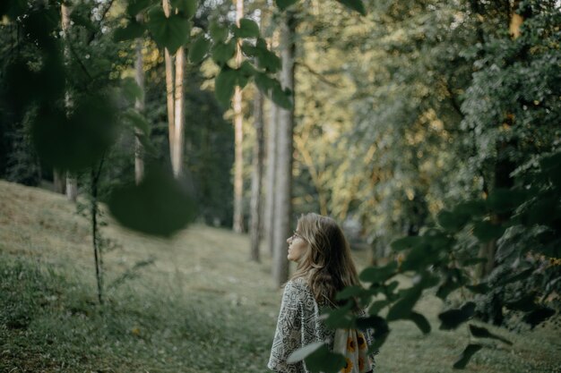 写真 森の植物のそばに立っている女性の後ろの景色