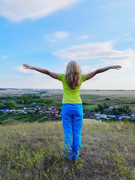 写真 空の向こうのフィールドに立っている女性の後ろの景色