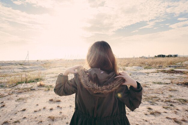 写真 空に照らされた風景に立っている女性の後ろの景色