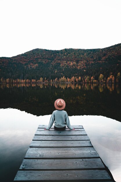 Фото Задний вид женщины, стоящей на пирсе над озером