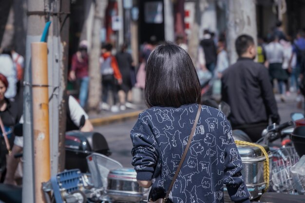 写真 街の通りに立っている女性の後ろの景色