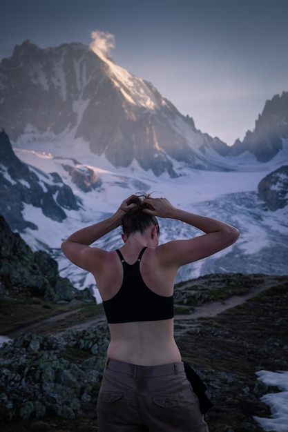 Фото Задний вид женщины, связывающей волосы, стоящей на горе зимой