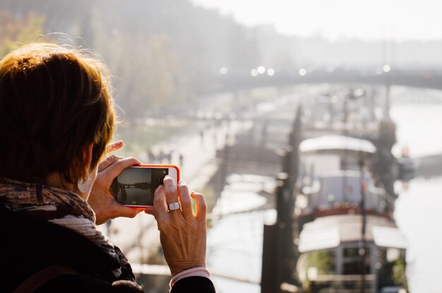 写真 都市で携帯電話を使っている女性の後ろの景色