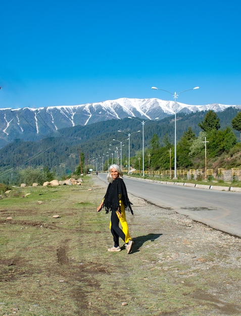 写真 山の向こうの道路を歩く女性の後ろの景色