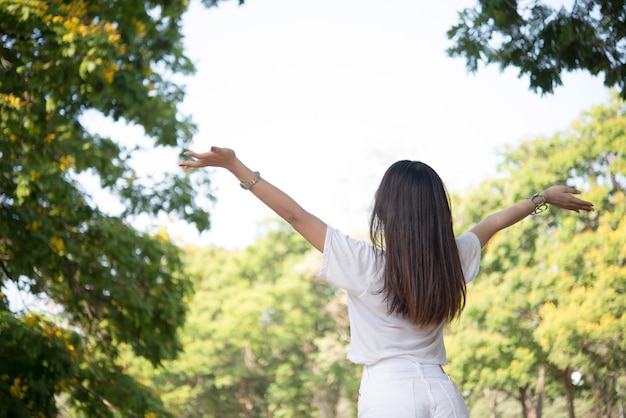 写真 腕を上げて木に立っている女性の後ろの景色