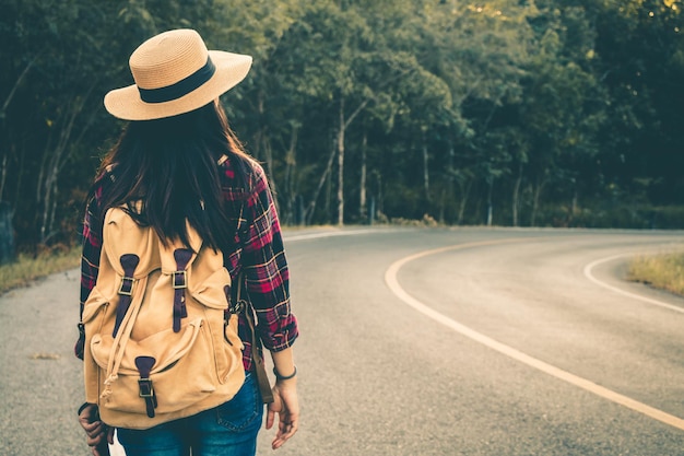 写真 道路に立っているバックパックを背負った女性の後ろの景色