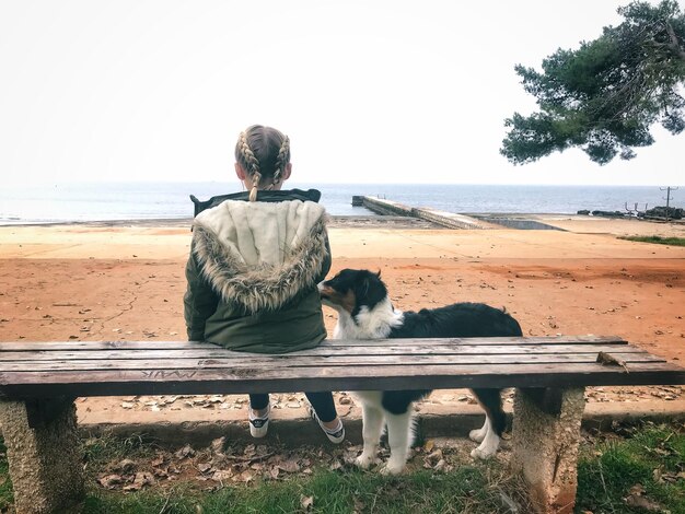 사진 해변 에 앉아 있는 개 와 함께 있는 여자 의 뒷면