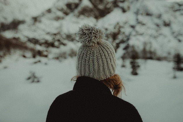 Фото Задний вид женщины с вязанной шляпой, стоящей против деревьев зимой
