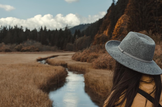 Фото Задний вид молодой женщины, восхищающейся прекрасным видом ручья в поле осенью