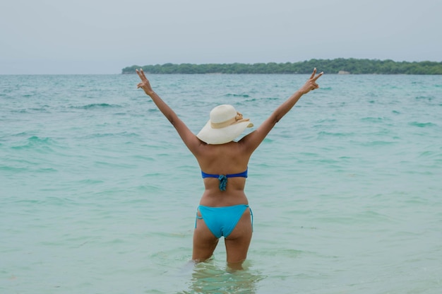 写真 腕を伸ばしてカルタヘナのコロンビアのカリブ海の海で水着姿の若い女性の背面図