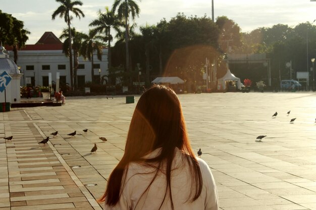 写真 空の向こうの通りに立っている若い女性の後ろの景色