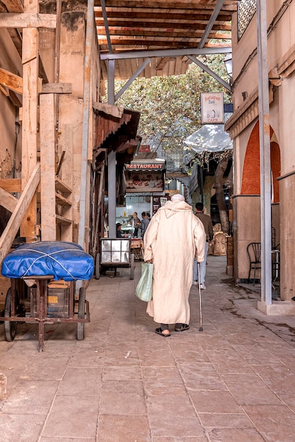 Rear view of old man in traditional djellaba walking on street