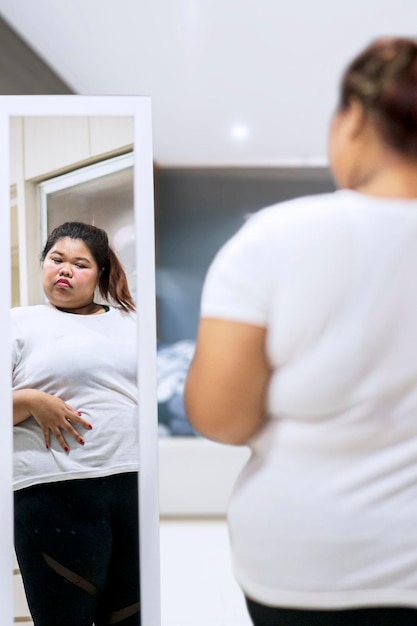 Photo rear view of overweight woman standing in front of mirror at home