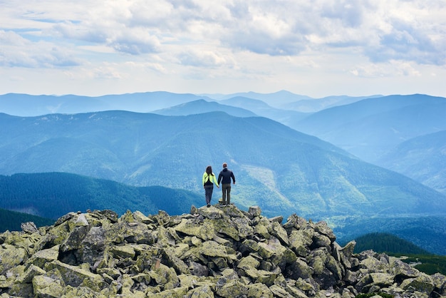 Rear view pair is holding hands and enjoying powerful view