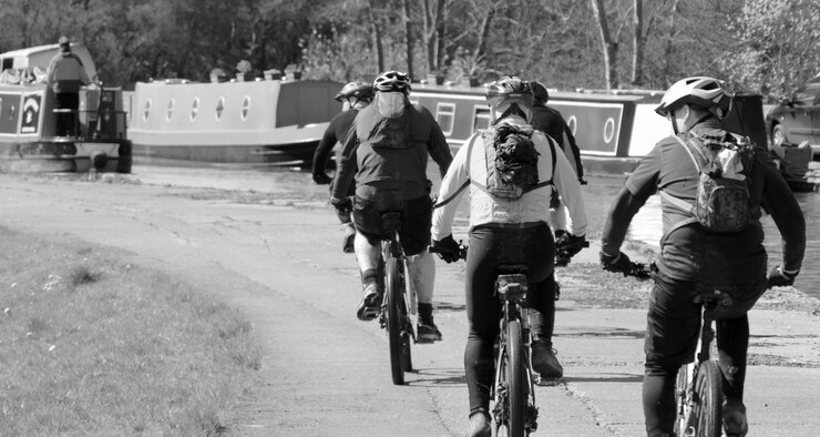 Photo rear view of people cycling by river