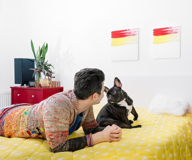 Rear view of people and dog relaxing on bed at home