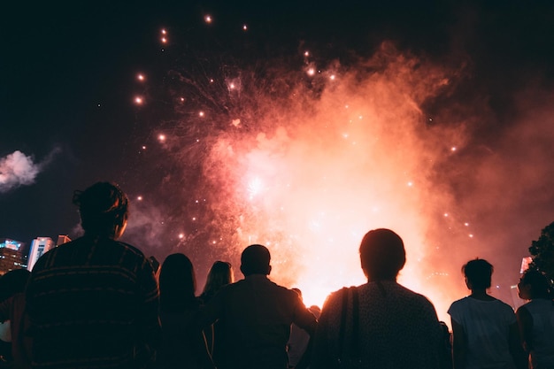 Foto vista posteriore di persone che si godono uno spettacolo di fuochi d'artificio di notte