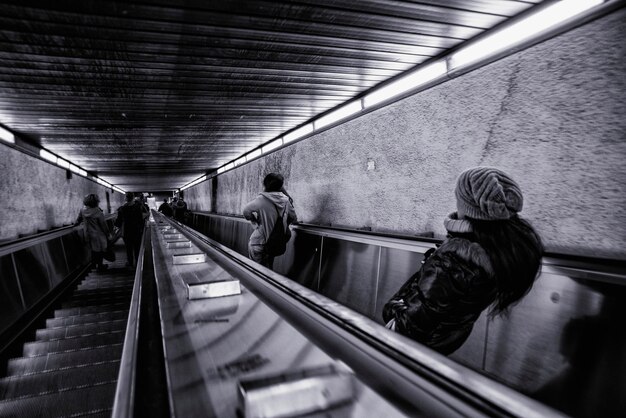 Photo rear view of people on escalators