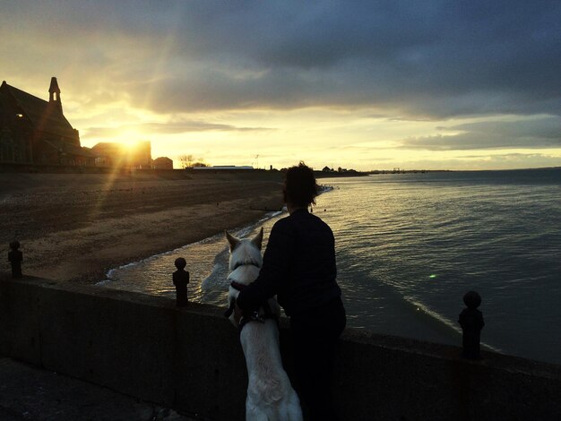 Foto vista posteriore di persone sul mare contro il cielo durante il tramonto