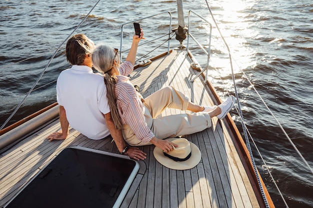 Rear view of people sitting on sailboat in sea