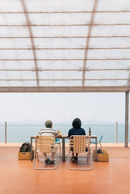 Rear view of people sitting on table at beach