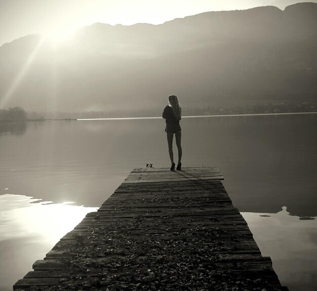 Foto vista posteriore di persone in piedi sul lago contro il cielo