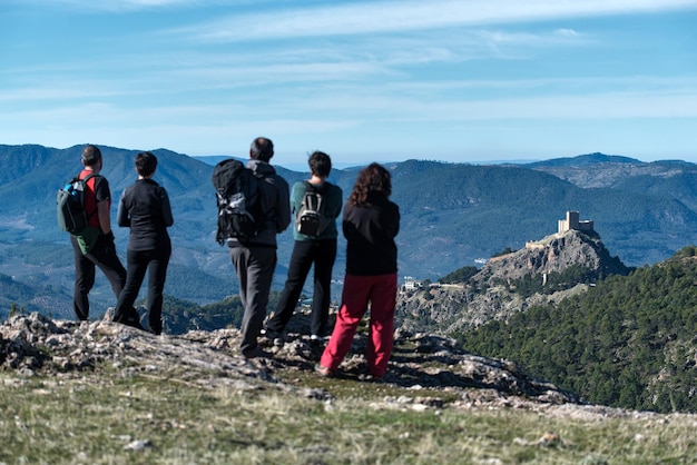 Rear view of people standing on mountain against sky