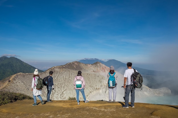 Rear view of people standing on mountain against sky