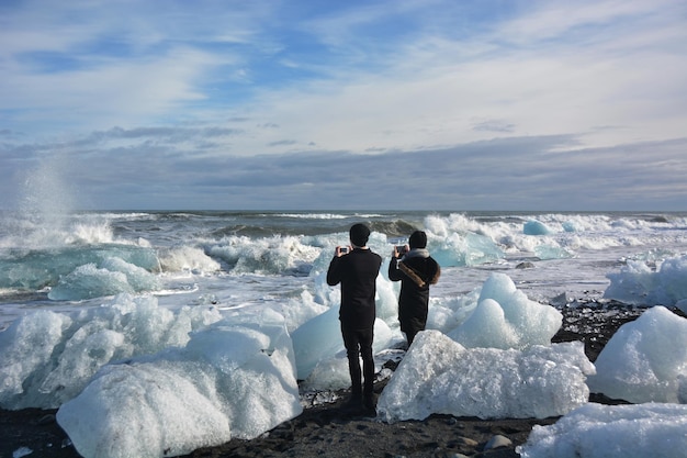 Foto vista posteriore di persone che scattano foto a formazioni di ghiaccio in mare