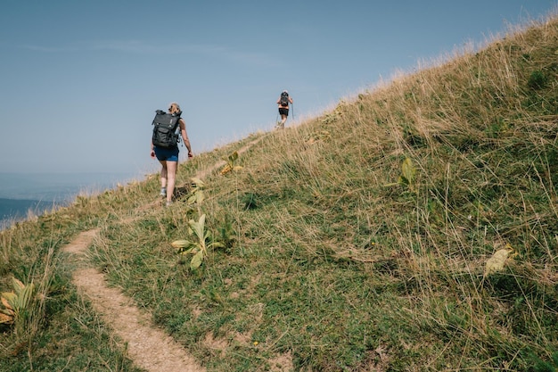 Rear view of people walking on grass against sky