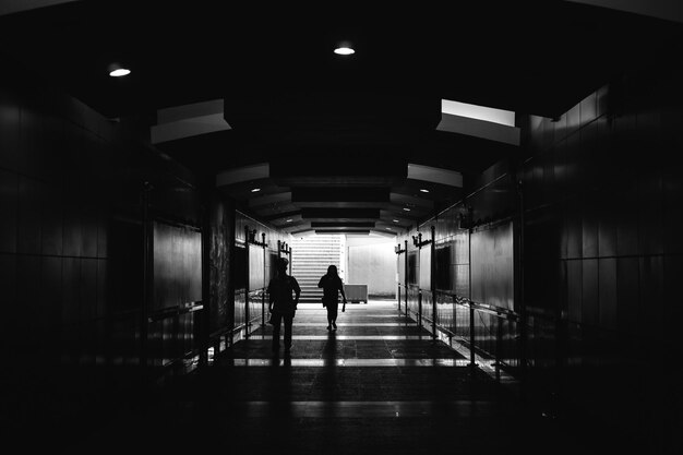 Photo rear view of people walking in illuminated tunnel