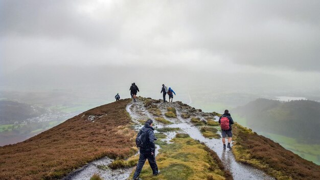 rear view of people walking on mountain against sky